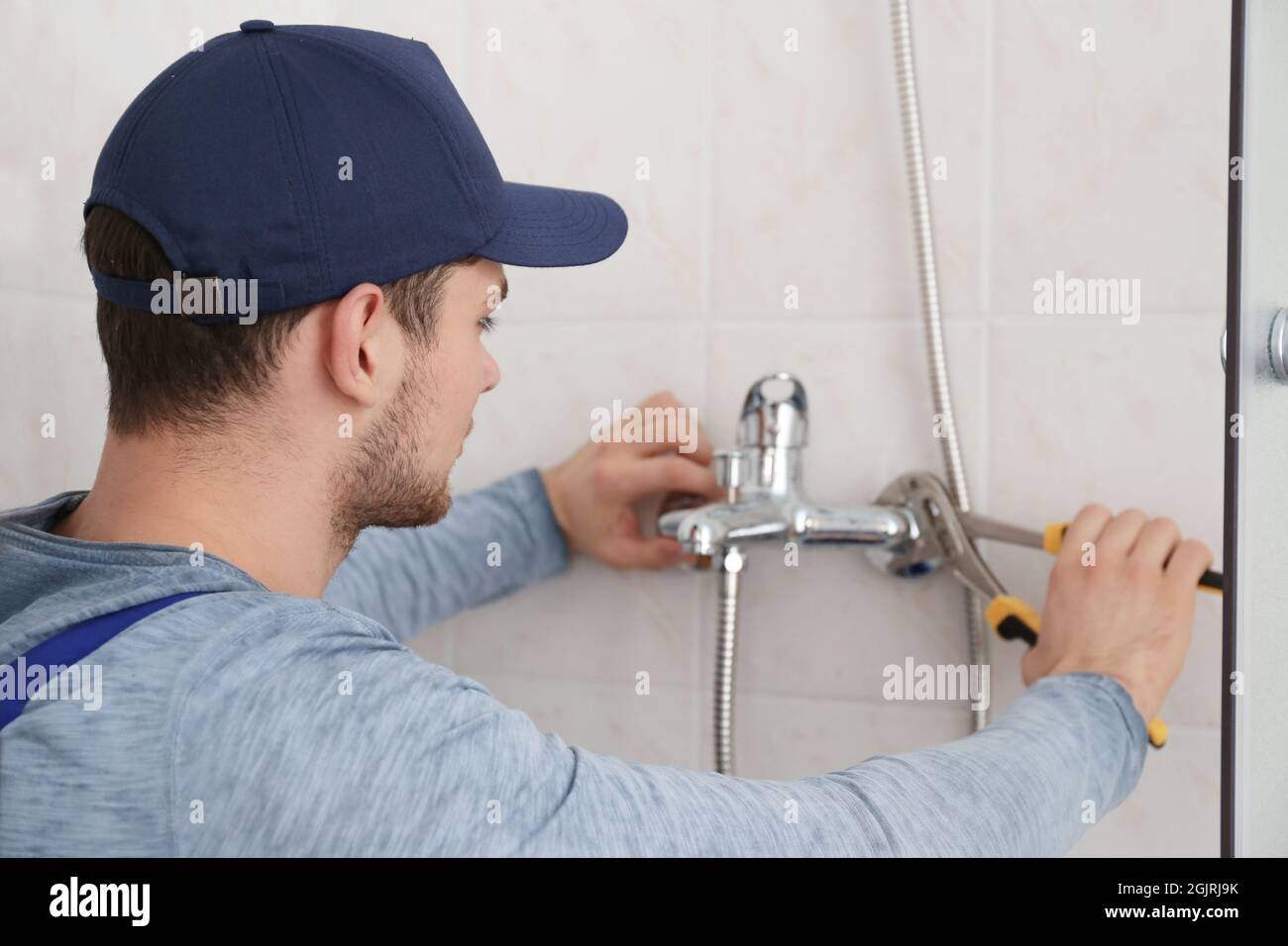 Plumber fixing faucet in shower stall Stock Photo Alamy