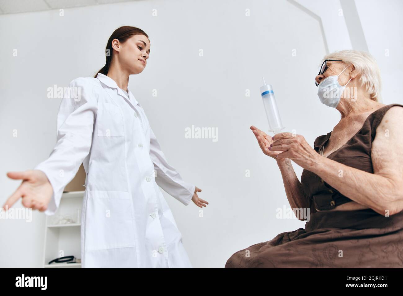 elderly woman at the doctor's appointment injection into the arm ...