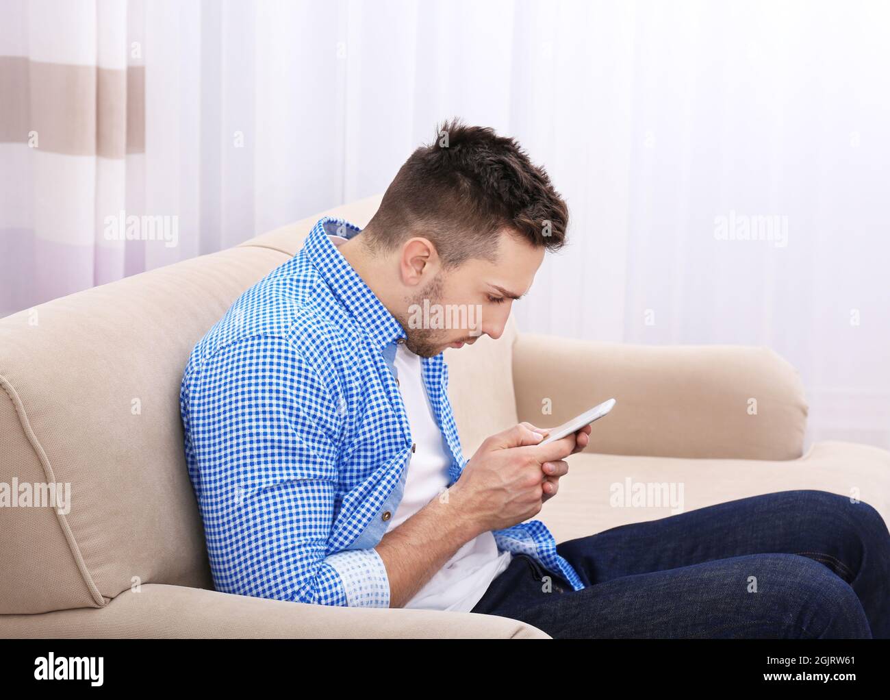 Handsome young man sitting on sofa at home. Incorrect posture concept Stock Photo Alamy