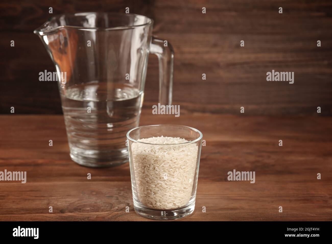 Glass Of Rice And Measuring Jug With Water On Wooden Table Stock Photo Alamy