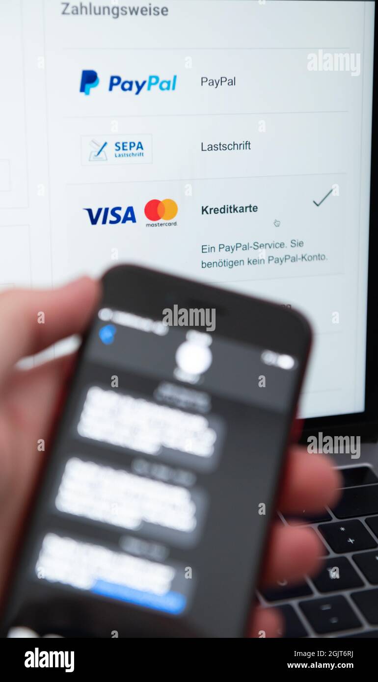 Rottweil, Germany. 09th Sep, 2021. A man holds his smartphone for two-factor authentication while a laptop screen displays various payment methods. Credit: Silas Stein/dpa/Alamy Live News Stock Photo