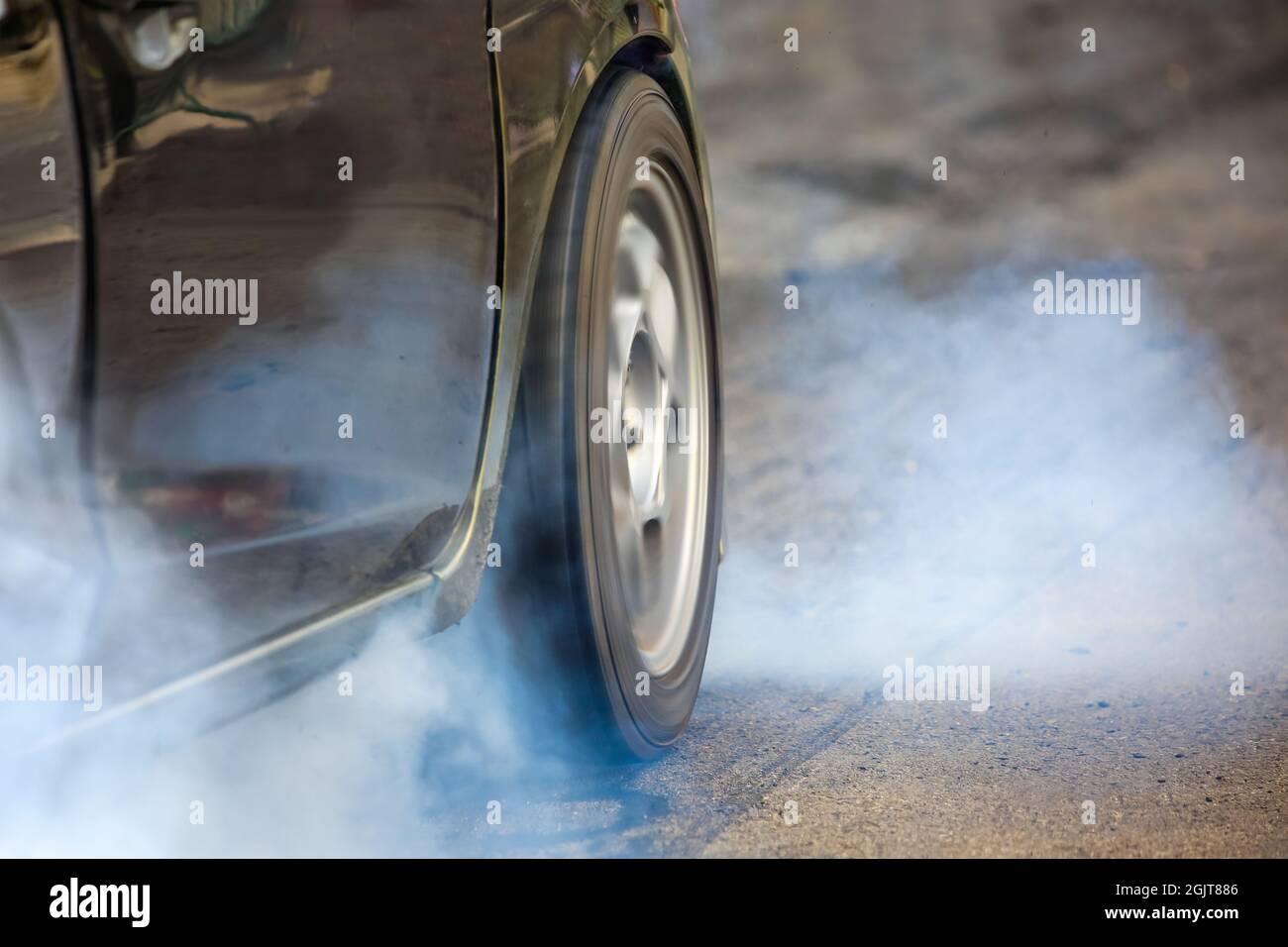 Front wheel drive drag race car burning tires at starting line Stock