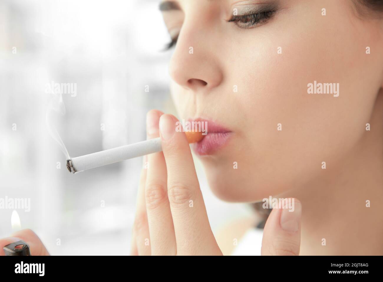 Young woman lighting cigarette at home Stock Photo Alamy