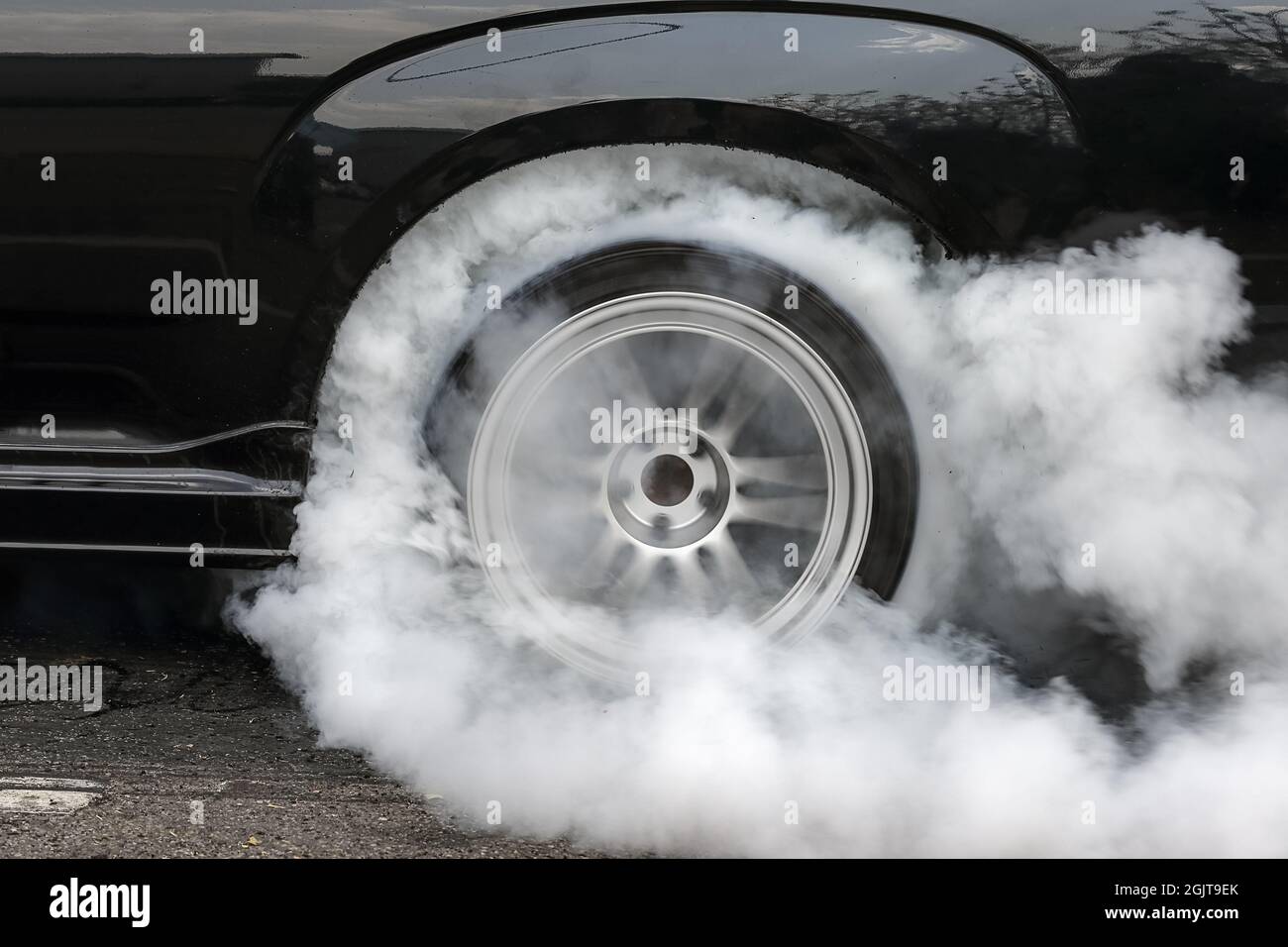 Drag racing car burns rubber off its tires in preparation for the race ...