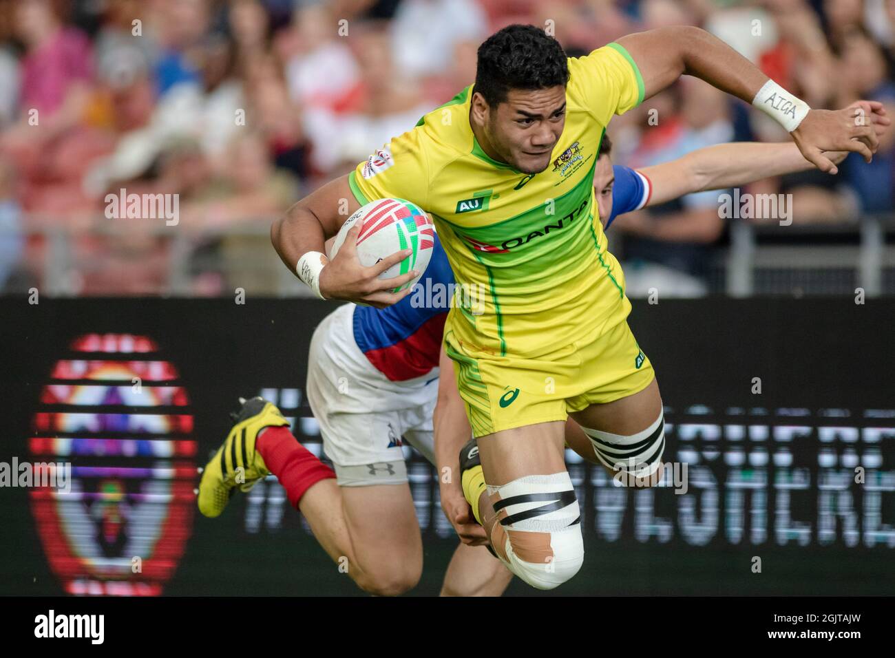 SINGAPORE-APRIL 13:Australia 7s Team (yellow) plays against France 7s team (blue/red) during Day 1 of HSBC World Rugby Singapore Sevens on April 13, 2019 at National Stadium in Singapore Stock Photo