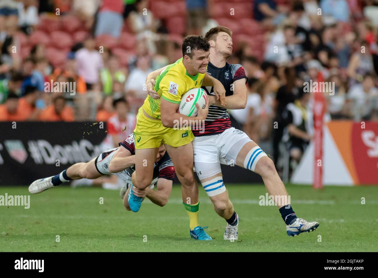 SINGAPORE-APRIL 13:Australia 7s Team (yellow) plays against Hong Kong 7s team (blue/red) during Day 1 of HSBC World Rugby Singapore Sevens on April 13, 2019 at National Stadium in Singapore Stock Photo