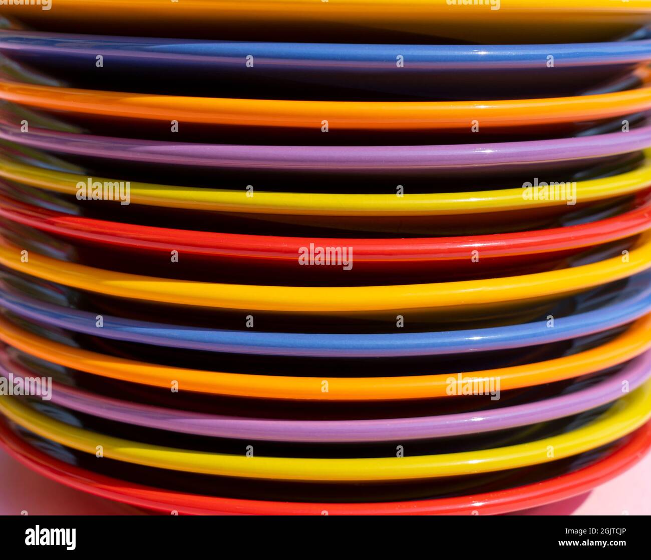 Different colored plates stacked. Dishes in red, orange, yellow, blue, purple and green. Rainbow colors and LGBT Stock Photo