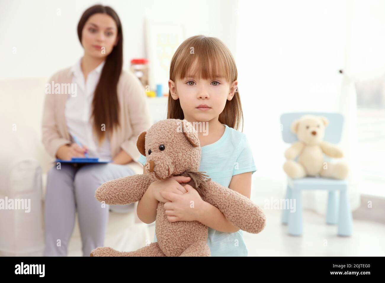 Little girl with teddy bear and child psychologist on background Stock ...