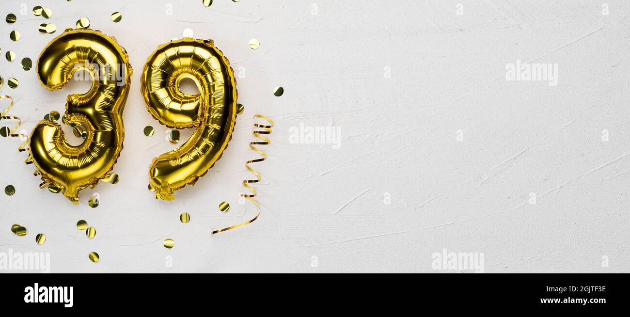 golden foil balloon number thirty nine. Birthday or anniversary card with the inscription 39. gray concrete background. Anniversary celebration. Banne Stock Photo