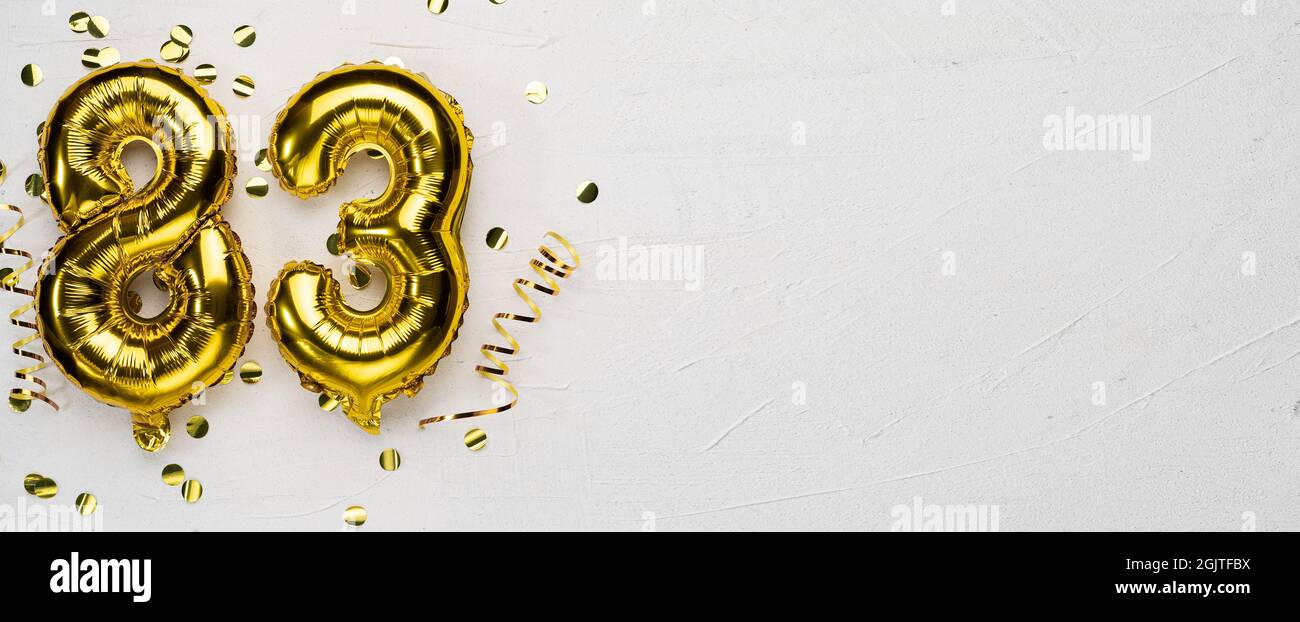 golden foil balloon number eighty three. Birthday or anniversary card with the inscription 83. gray concrete background. Anniversary celebration. Bann Stock Photo