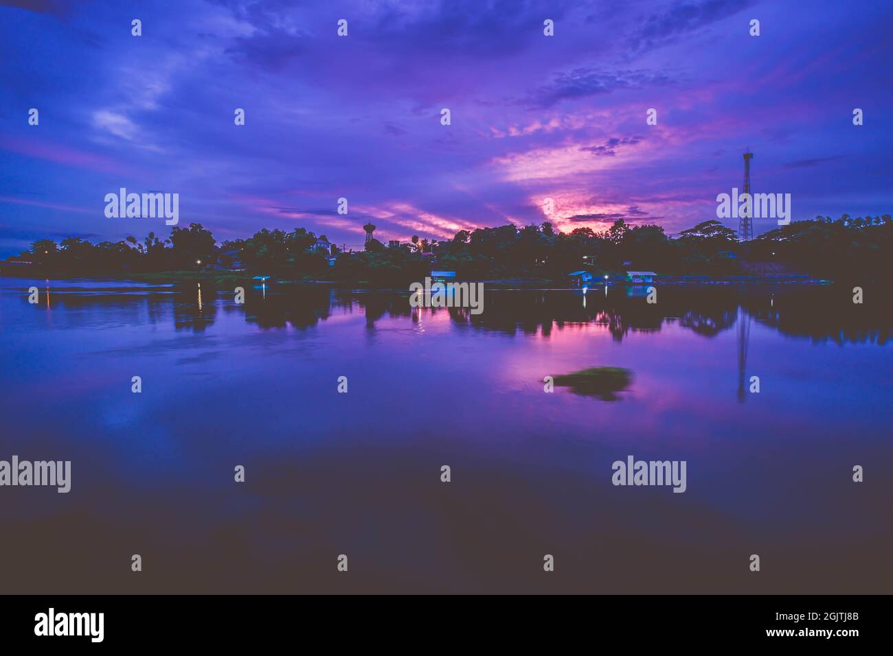 sunrays spread over the sky at dusk. Water reflection at sunset ...