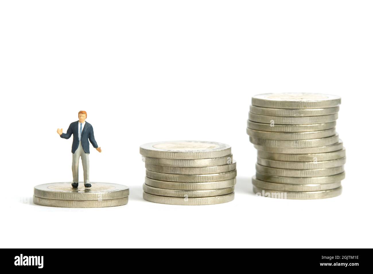 Miniature people toy figure photography. Financial plan concept. A shrugging businessman stand above increasing coin money stack. Isolated on white ba Stock Photo
