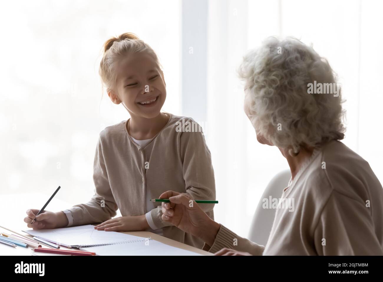 Happy little kid drawing with caring granny. Stock Photo