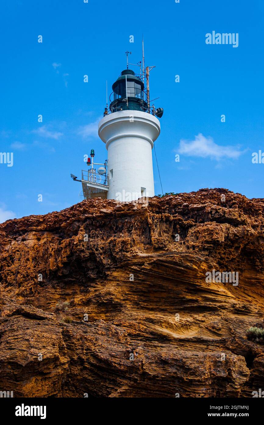 Point Lonsdale Lighthouse standing tall on a rocky cliff edge. Stock Photo
