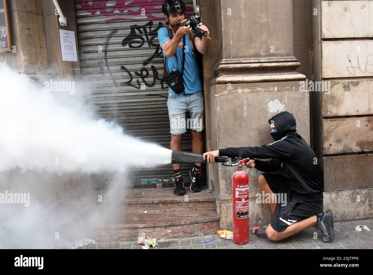 Barcelona, Spain. 11th Sep, 2021. A protester throws the powder from a fire extinguisher at the Catalan Police during the demonstration of the National Day of Catalonia.Pro-independence protesters during the National Day of Catalonia confront the Catalan Police (Mossos d'Escuadra) for throwing cans of paint, smoke, some cans, fire extinguishers, bottles and iron bars at the Spanish Police at their headquarters in Barcelona in protest for the police charges carried out in the illegal referendum of 2017. (Photo by Ramon Costa/SOPA Images/Sipa USA) Credit: Sipa USA/Alamy Live News Stock Photo