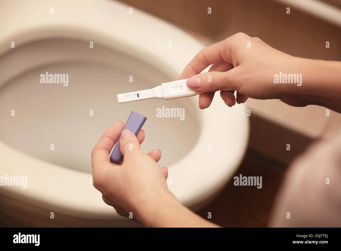 Pregnancy test in hands on bathroom background Stock Photo - Alamy