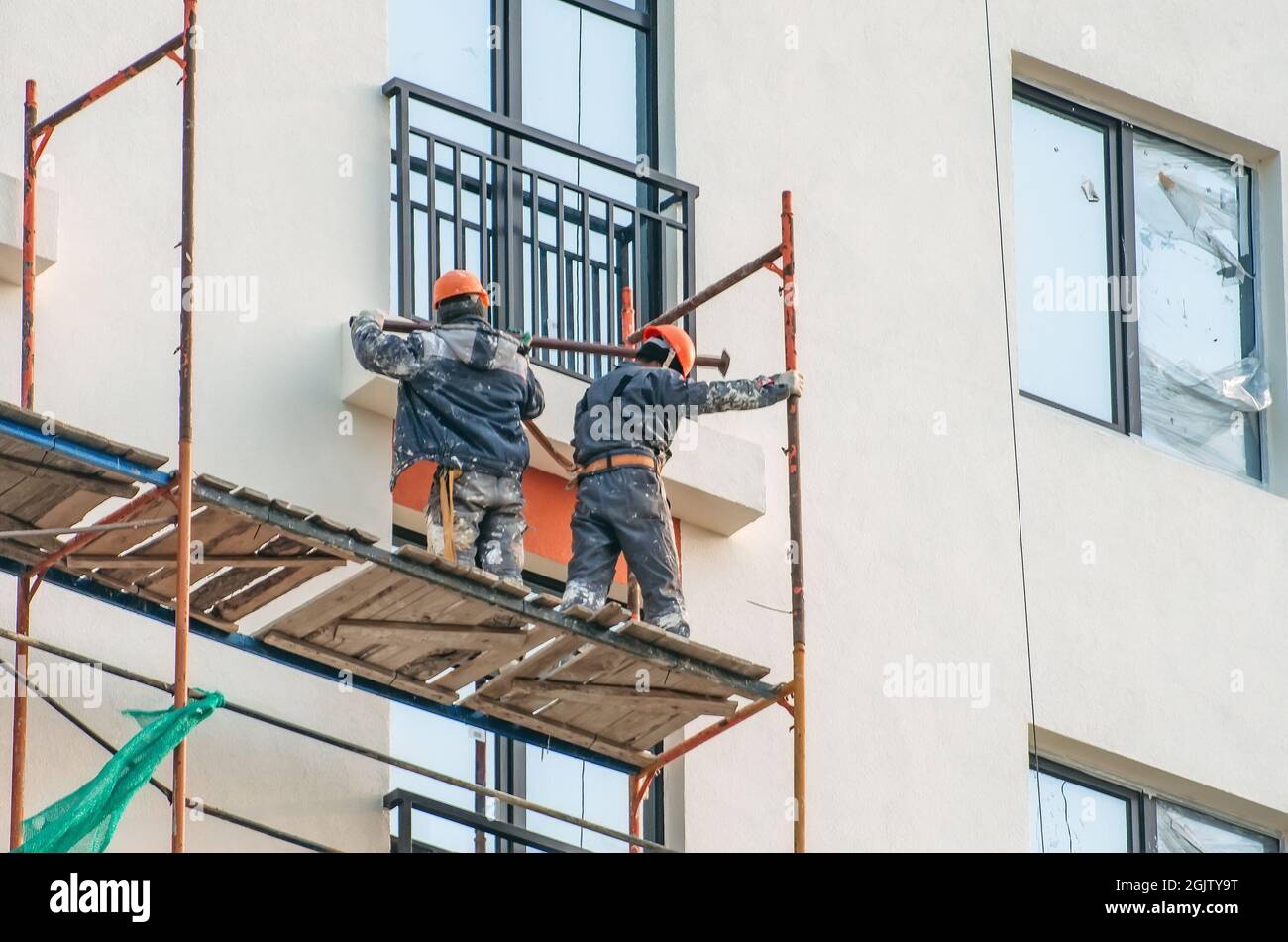 Two workers assembling scaffolding on city building Stock Photo