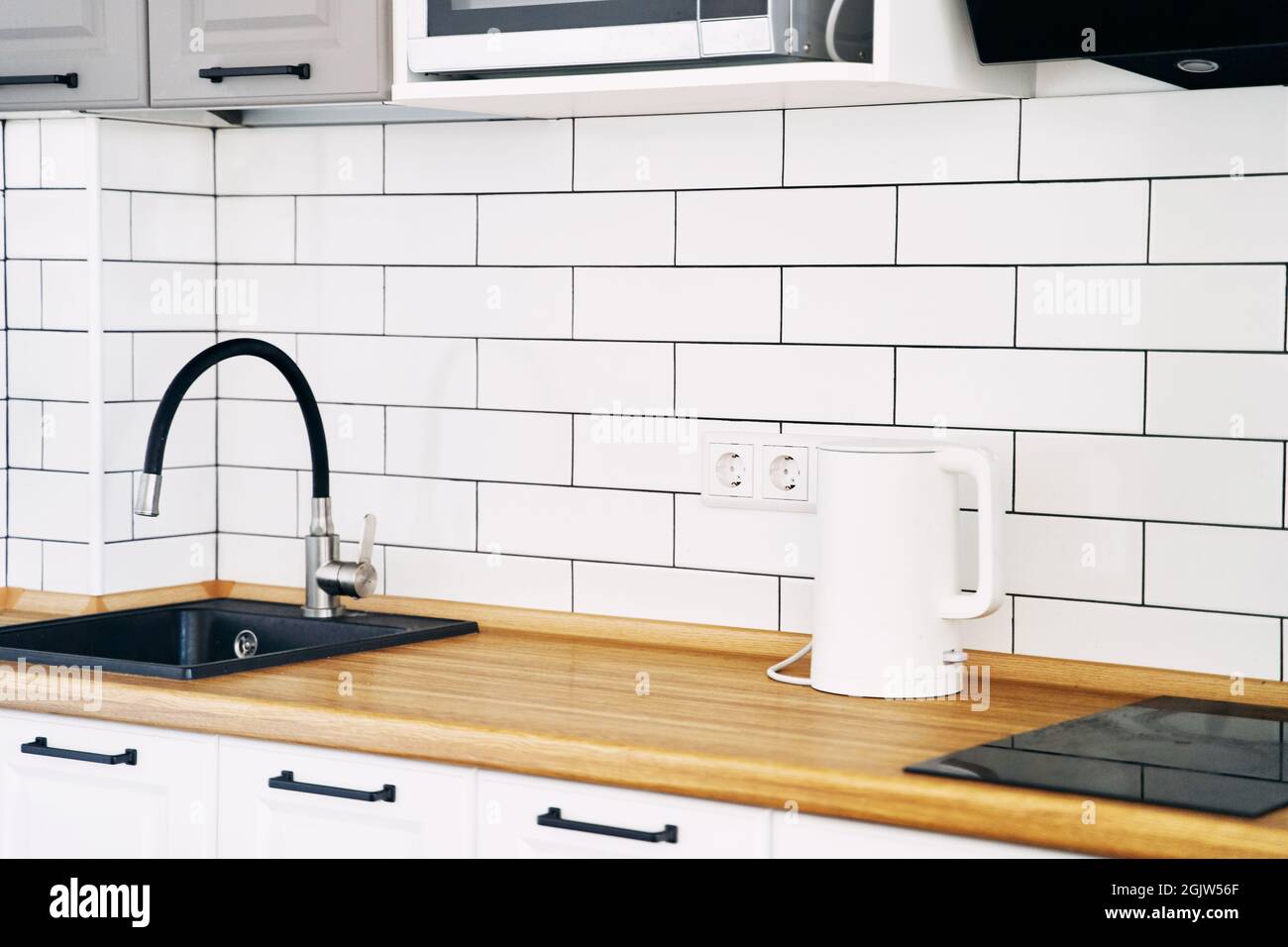 White cabinets with wooden counter of modern kitchen Stock Photo - Alamy