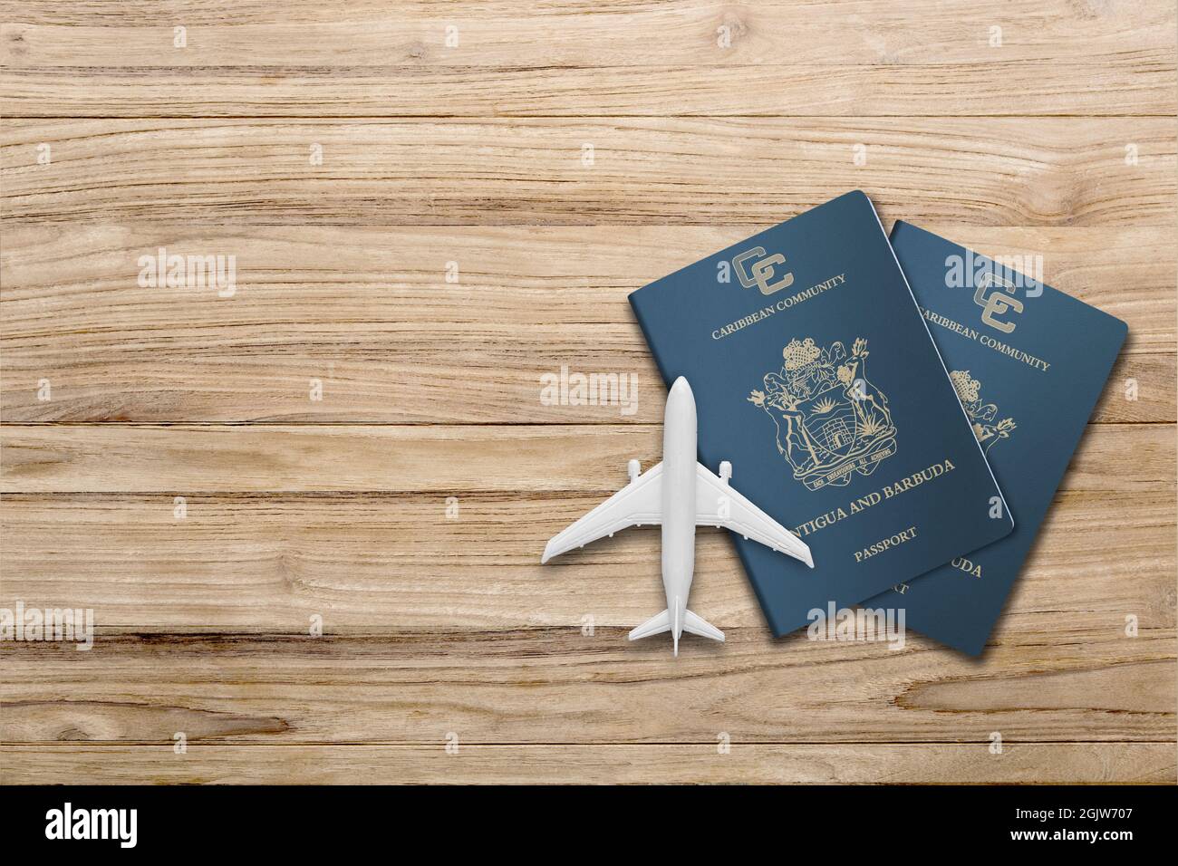 Plane model and antigua and barbuda passport  on wooden background, flat lay. Space for text Stock Photo