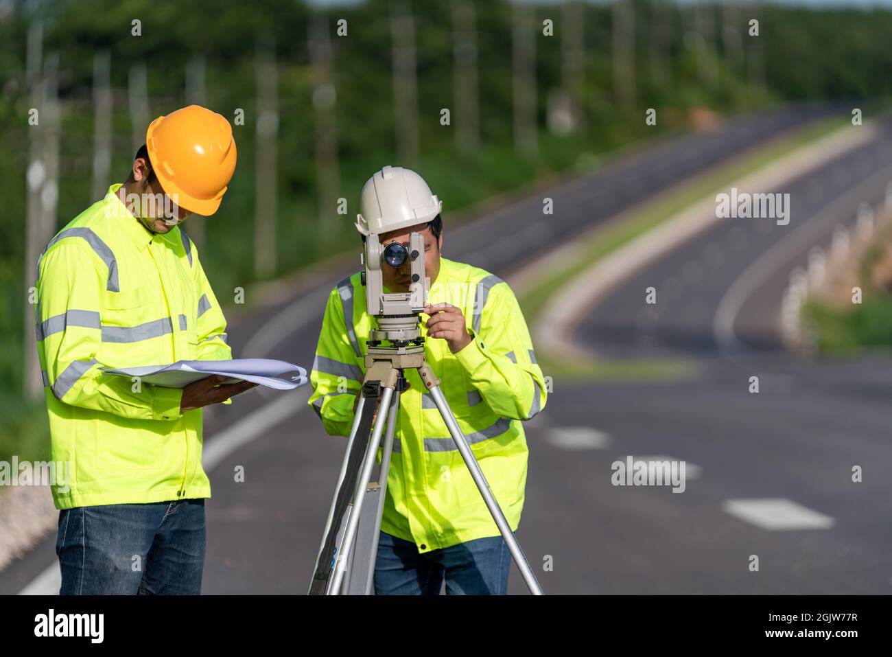 Two surveyor engineers with equipment on road construction site, Civil