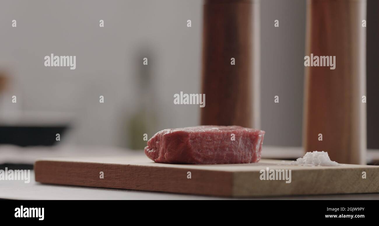 salting beef steak on wood board with sea salt flakes, wide photo Stock
