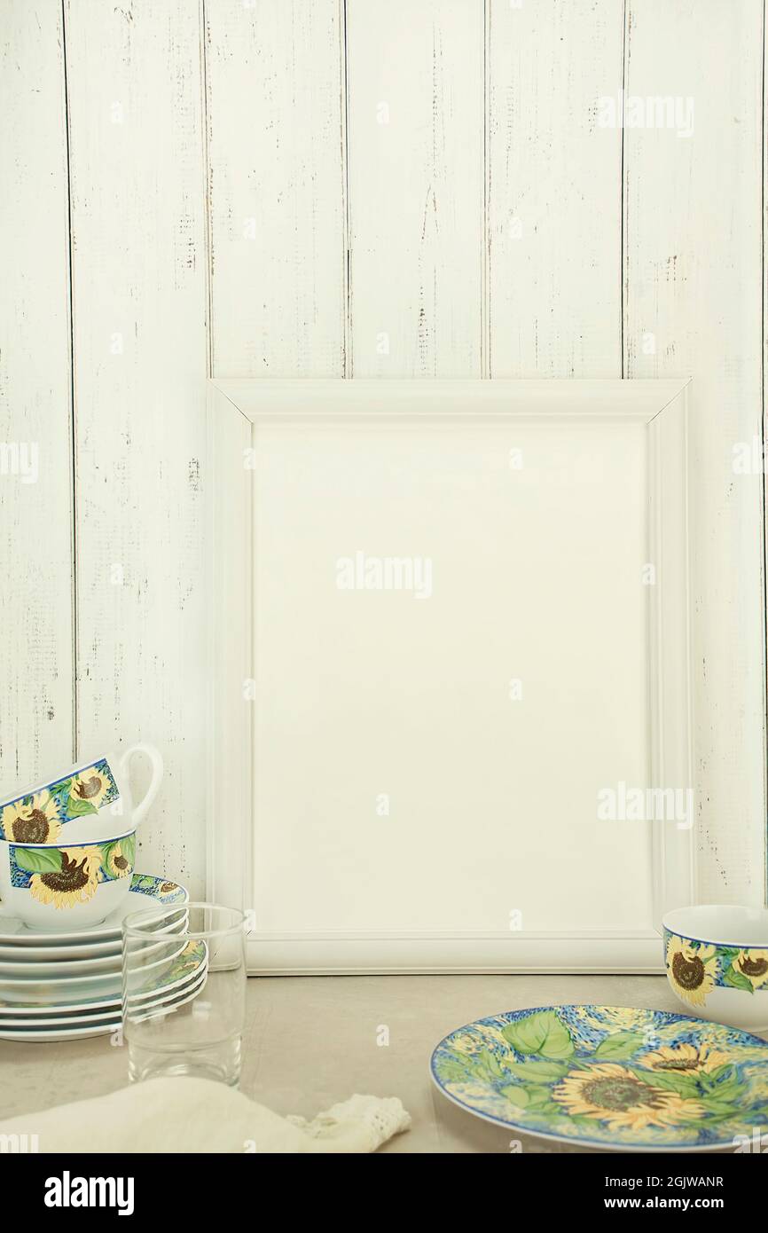 Empty white frame mockup with dishes on table against white wall background Stock Photo