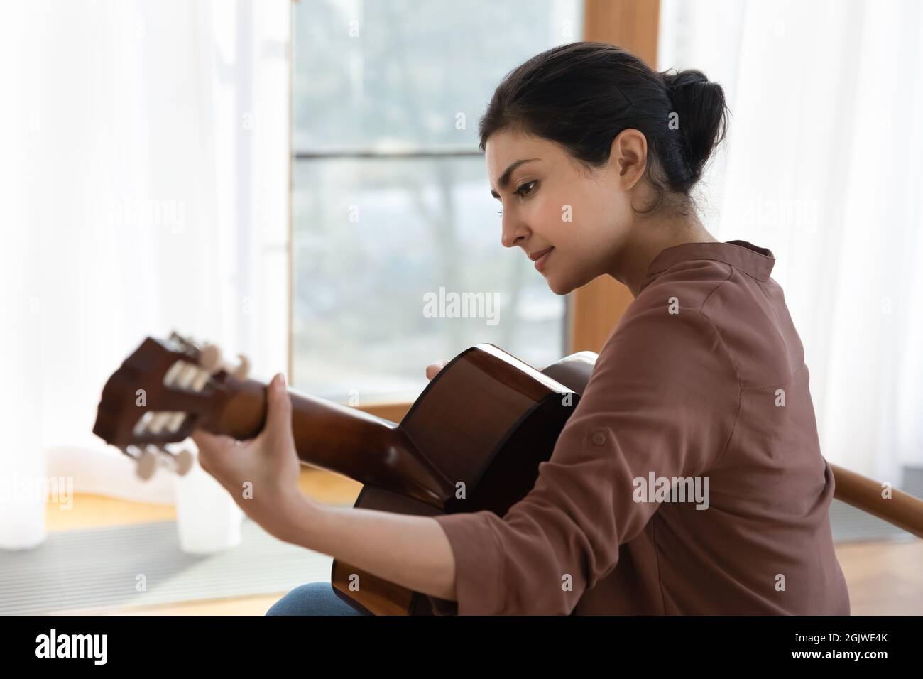 Inspired young indian female guitarist hold guitar play lyrical melody Stock Photo