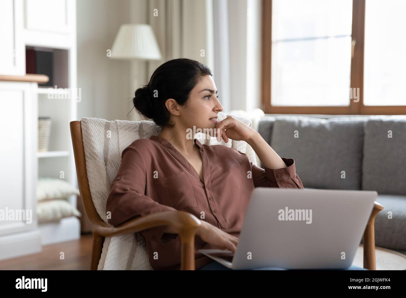 Thoughtful young indian female hold laptop ponder distracted from screen Stock Photo