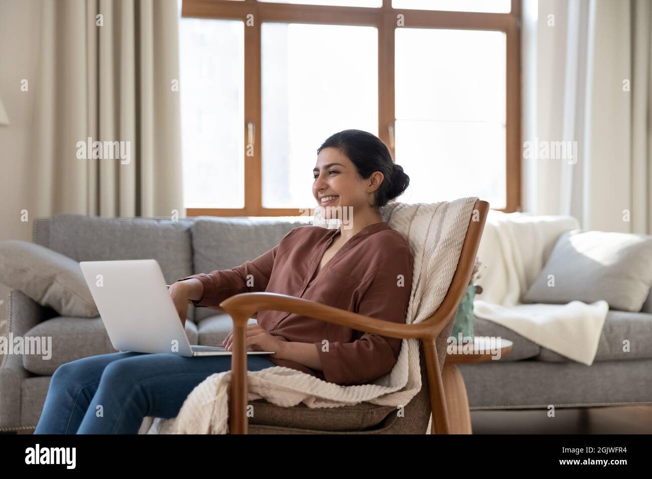 Smiling young indian woman enjoy weekend at home by pc Stock Photo