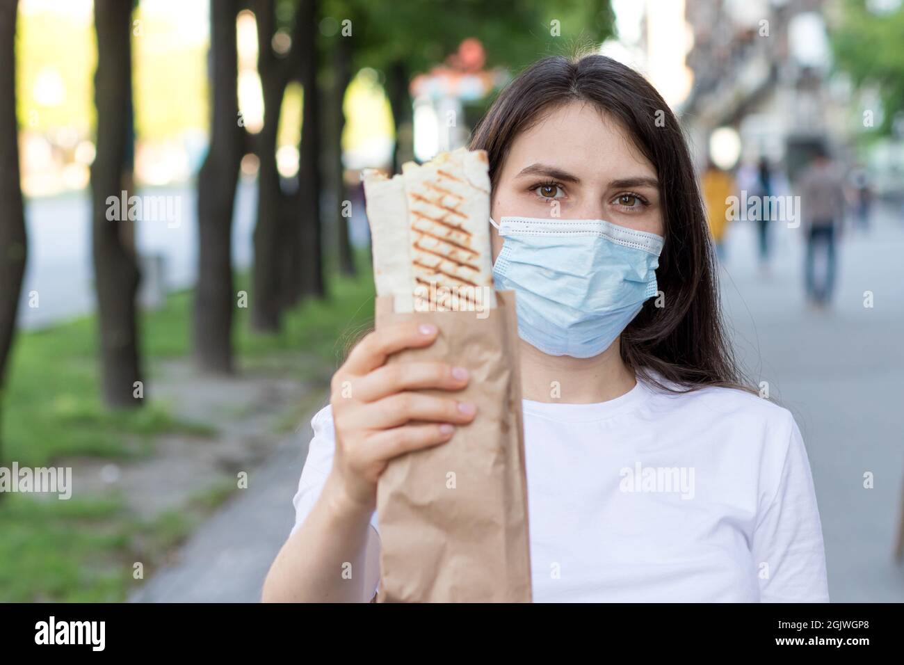A masked deliverywoman holds an order - fast food, street food and home ...