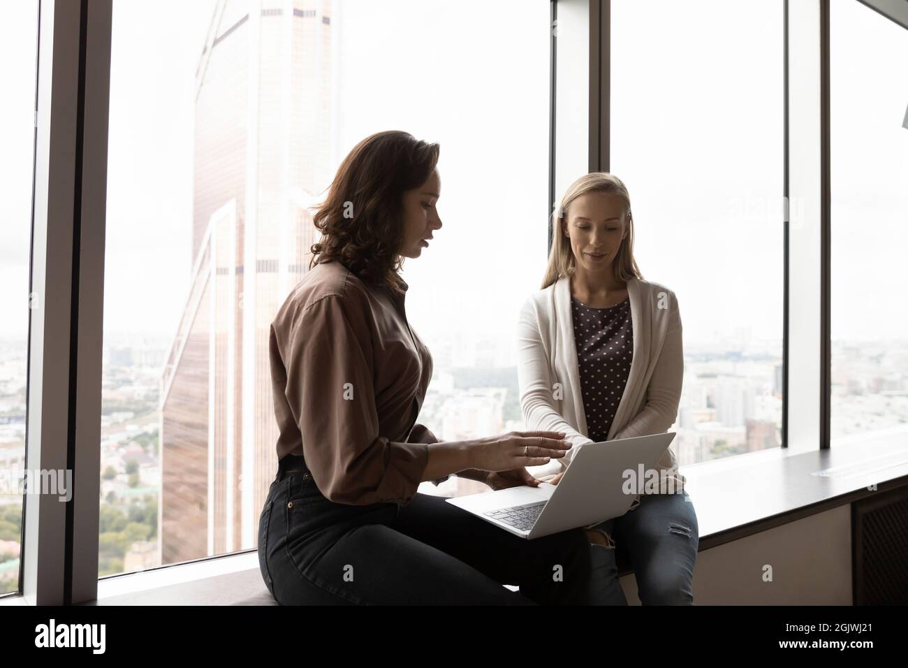 Women employees brainstorm discussing project on computer Stock Photo