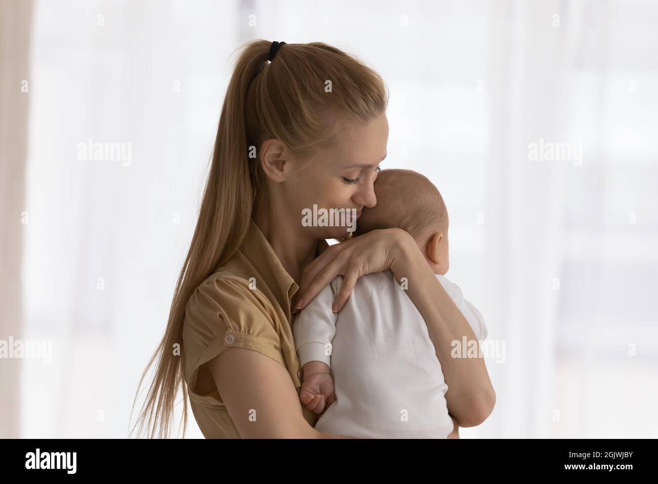 Happy young mom holding and hugging adorable few month baby Stock Photo