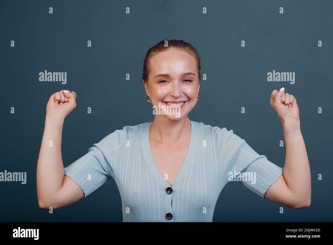 Young woman winner joy and throws his hands up raised arms in the air ...