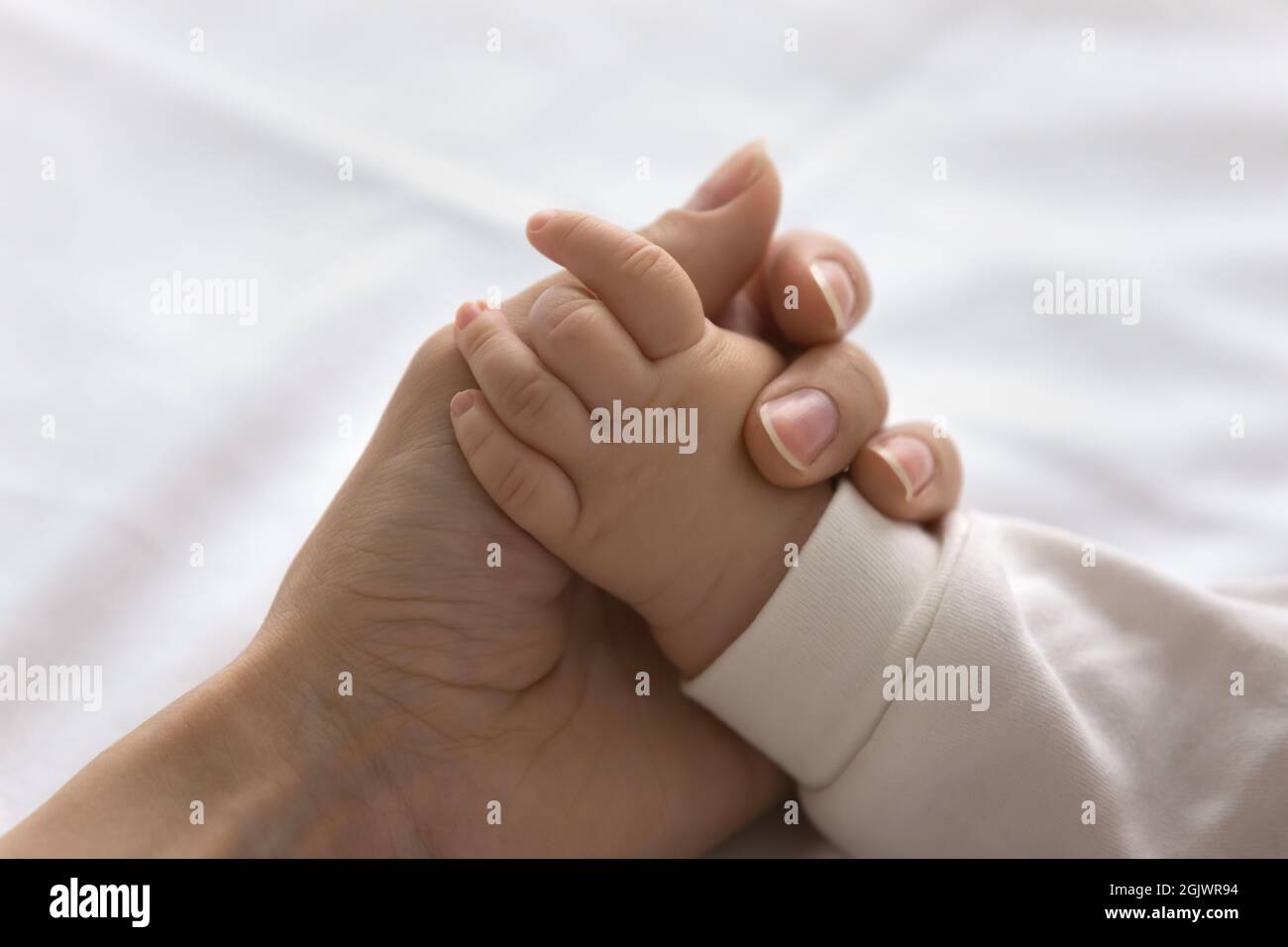 Young mom touching little palm of little baby Stock Photo