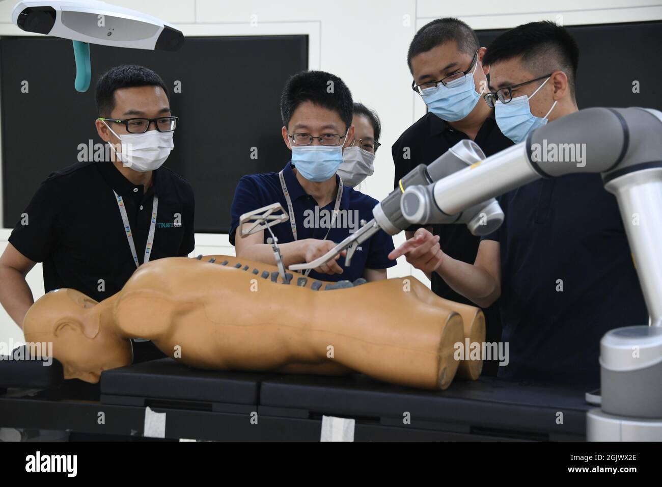 (210912) -- BEIJING, Sept. 12, 2021 (Xinhua) -- Liu Tiechang (2nd L) and his colleagues of Tinavi, a Chinese tech company that specializes in the development of orthopedic surgical robots, work in a lab in Beijing, capital of China, Aug. 4, 2021. The orthopedic surgical robot could dynamically analyze the patient's anatomy as well as the spine-hip relation and carry out the individualized surgery planning exactly as planned. Beijing Haidian Hospital officially introduced orthopedic surgery robots from May 2020, and has completed more than 400 robotic surgeries by the end of August 2021. (Xinhu Stock Photo