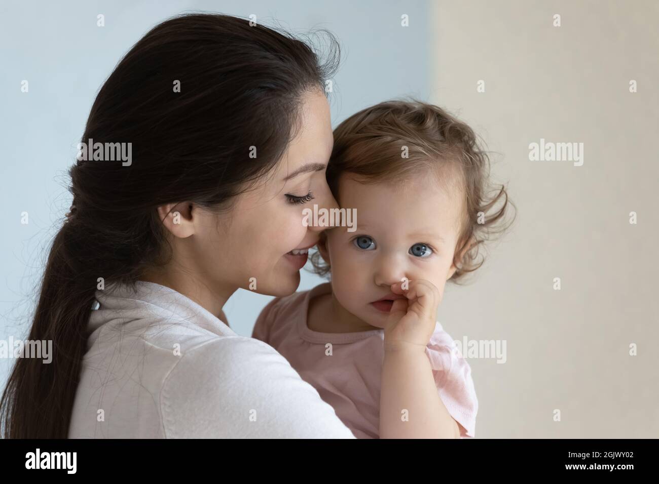 Happy new mom holding cute toddler baby in arms, smiling Stock Photo