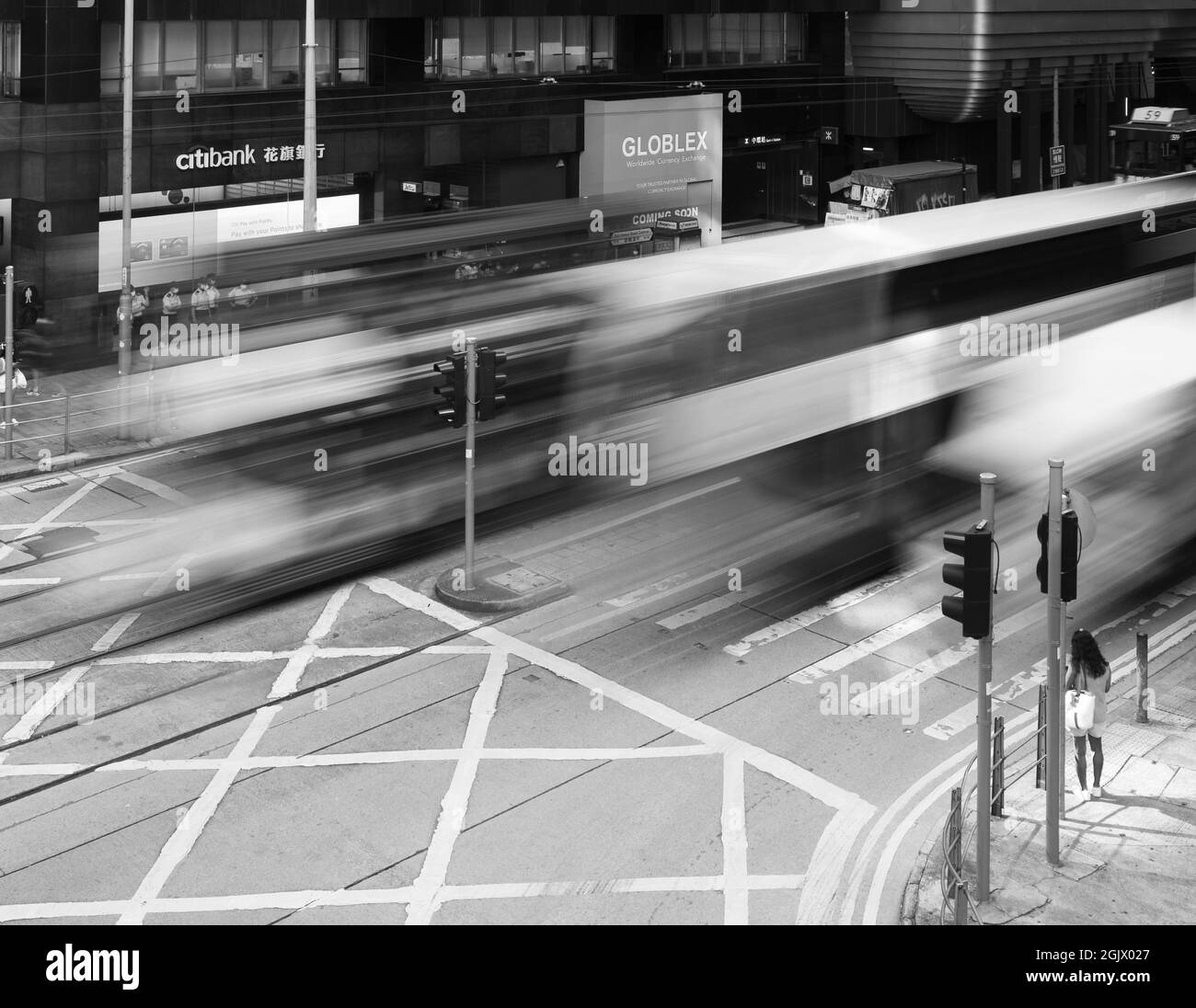 Person waiting to cross a road.  Long exposure gives blurred images of vehicles in Central, Hong Kong. Stock Photo