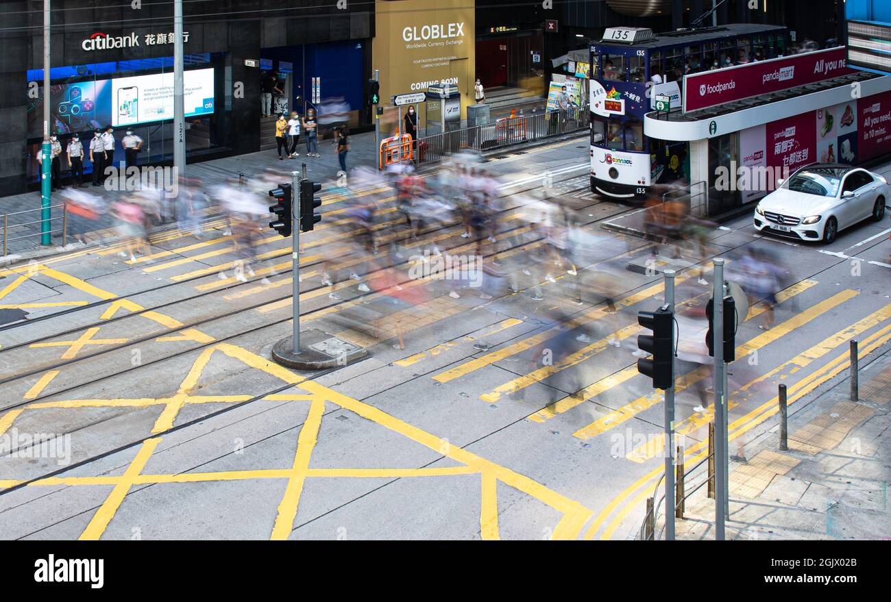 Long exposure of people crossing a road blurs their motion Stock Photo