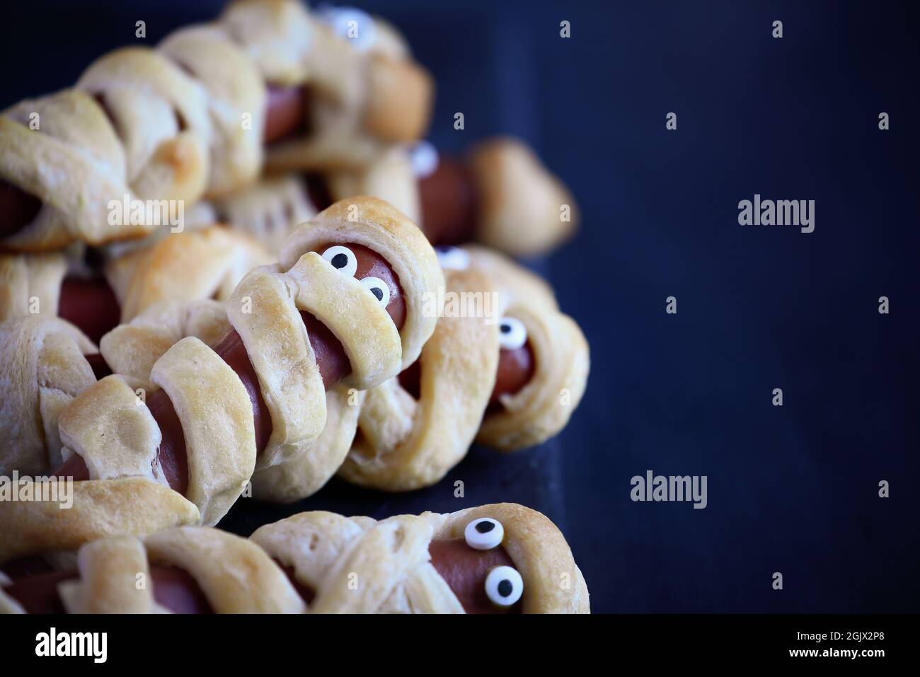 Fun food for kids. Group of mummy hot dogs on a blue rustic table. Selective focus with blurred foreground and background. Stock Photo