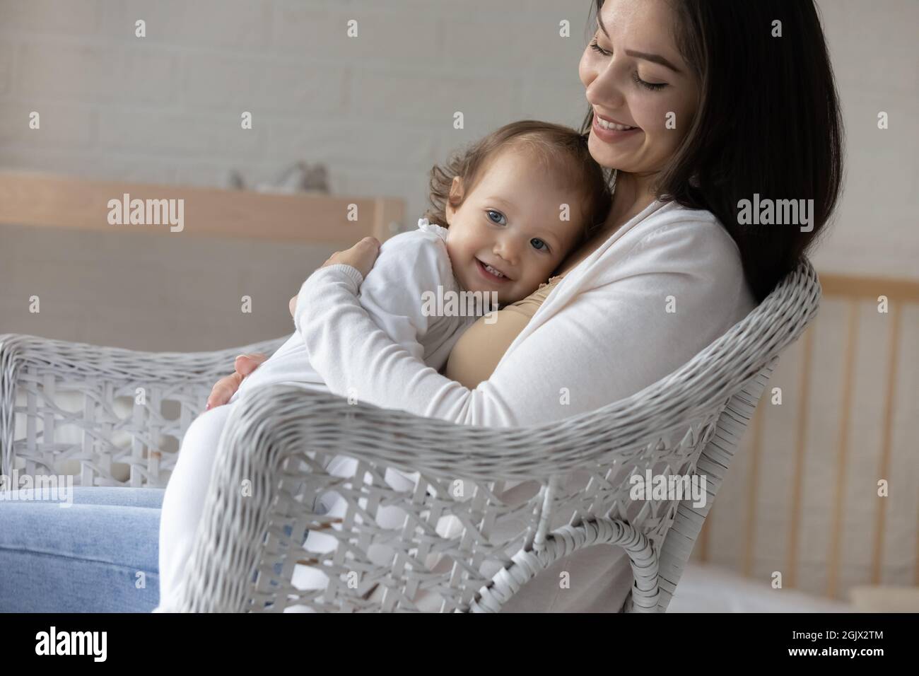 Smiling young mom hugging and cuddling little baby daughter Stock Photo