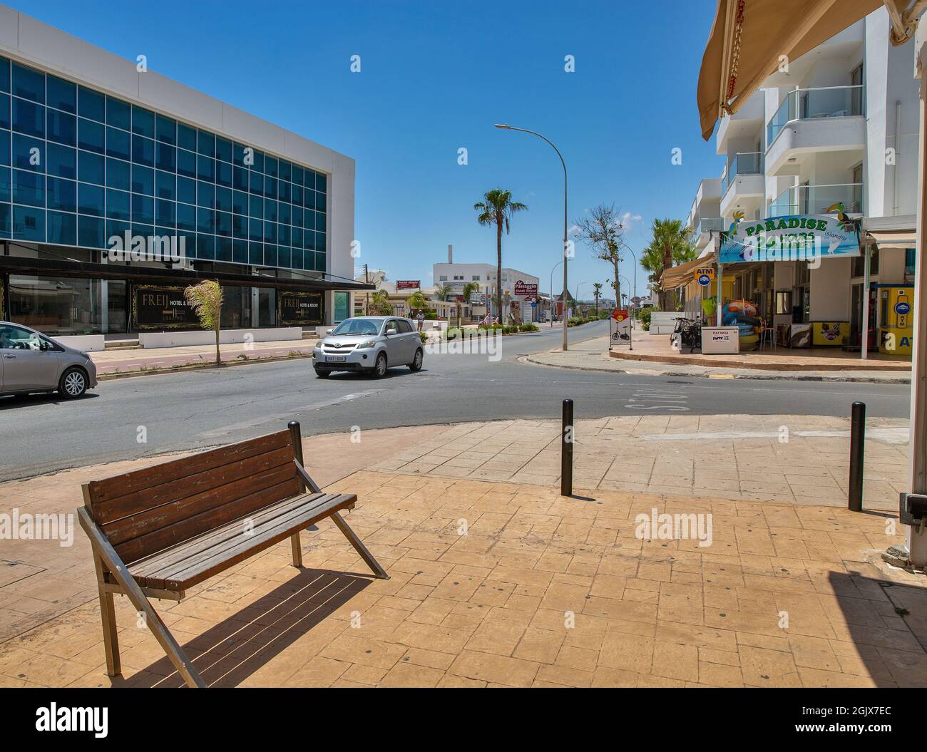 AYIA NAPA, CYPRUS - MAY 23, 2021: People sytroll along summer sunny Nissi Avenue and Freij Hotel in city center. Ayia Napa is a tourist resort at the Stock Photo