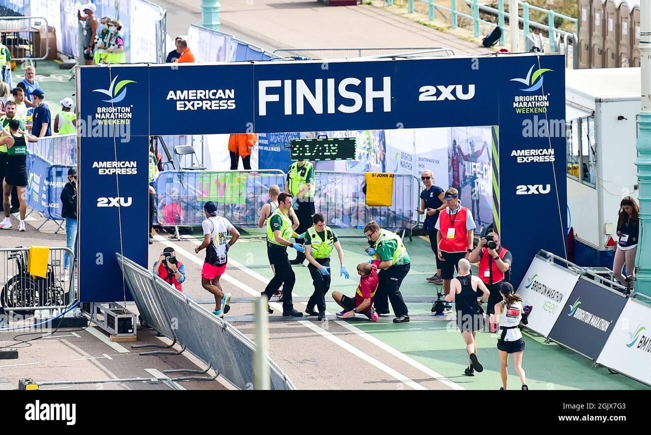 Brighton UK 12th September 2021 - A runner gets help at the finishing line as thousands take part in the Brighton Marathon today after last years race was cancelled due to the COVID-19 lockdown restrictions : Credit Simon Dack / Alamy Live News Stock Photo