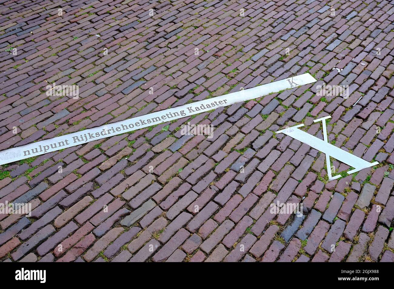 Pavement with x-axis of the Netherlands national triangle system. Dutch text: zero point national triangular measurement cadastre. Building Onze Lieve Stock Photo