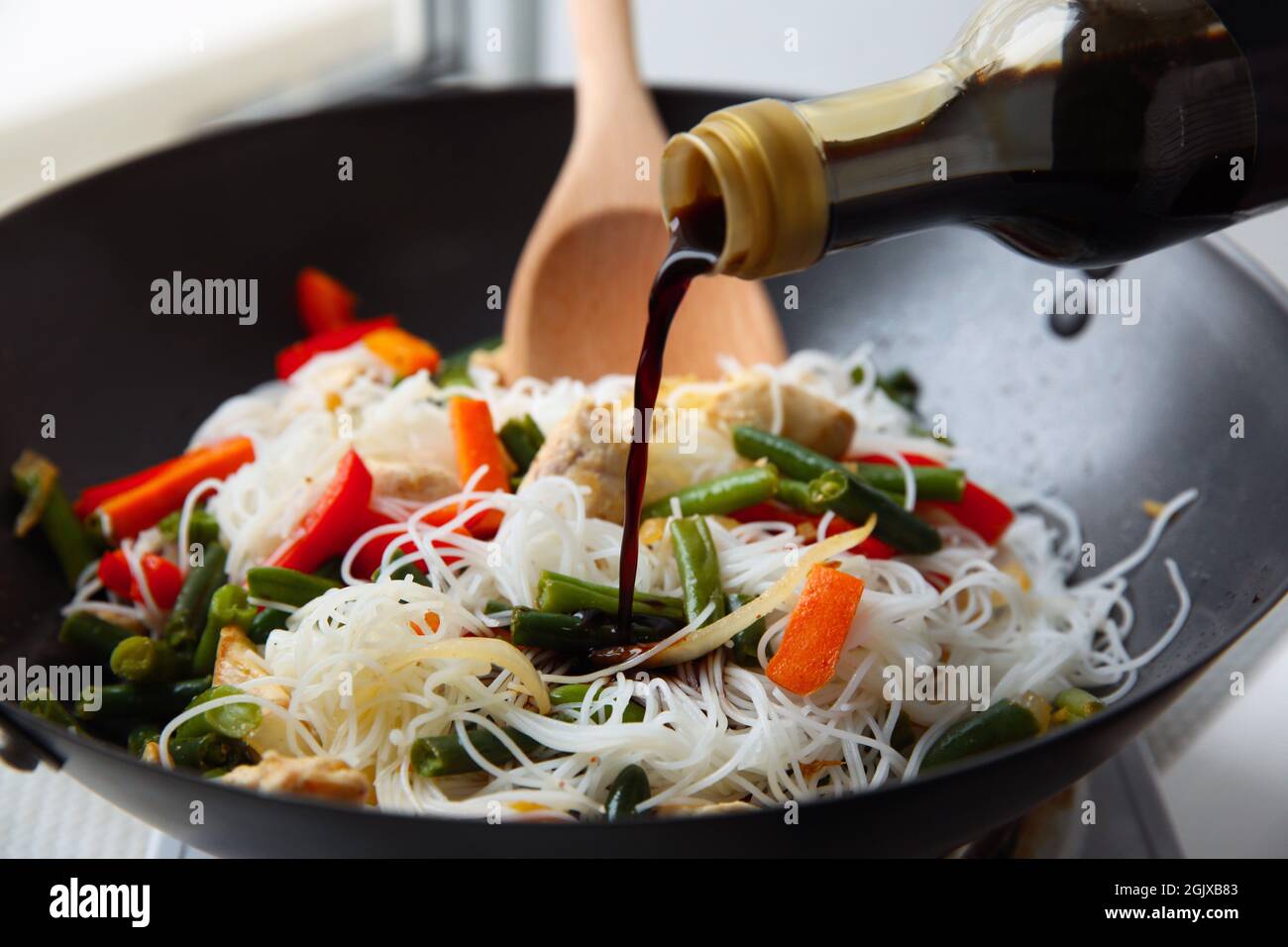 Adding soy sauce to rice noodle with vegetables in wok Stock Photo Alamy