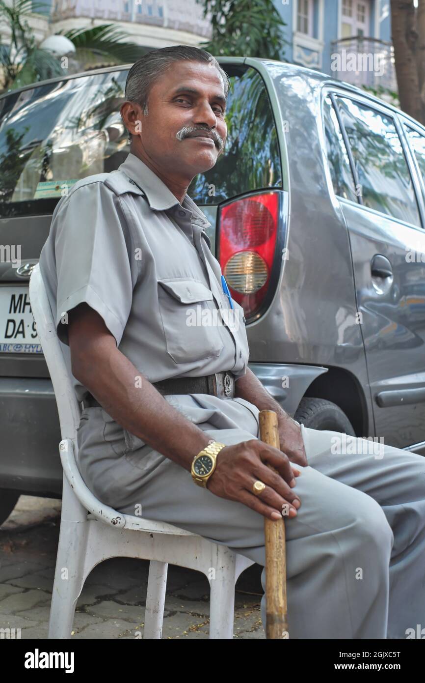 A watchman in Colaba, Mumbai, India, privately employed to keep order in a small lane occupied by well-do-do residents and armed with a lathi (stick) Stock Photo