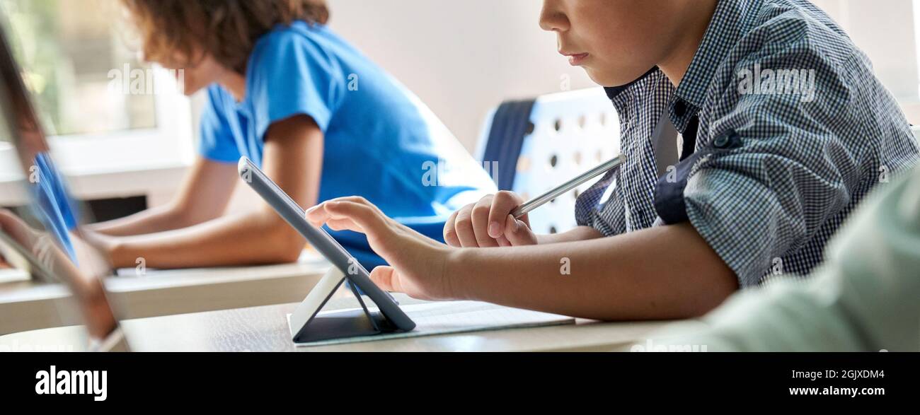 Concentrated Asian schoolboy using tapping tablet. Close up. Cut. Stock Photo