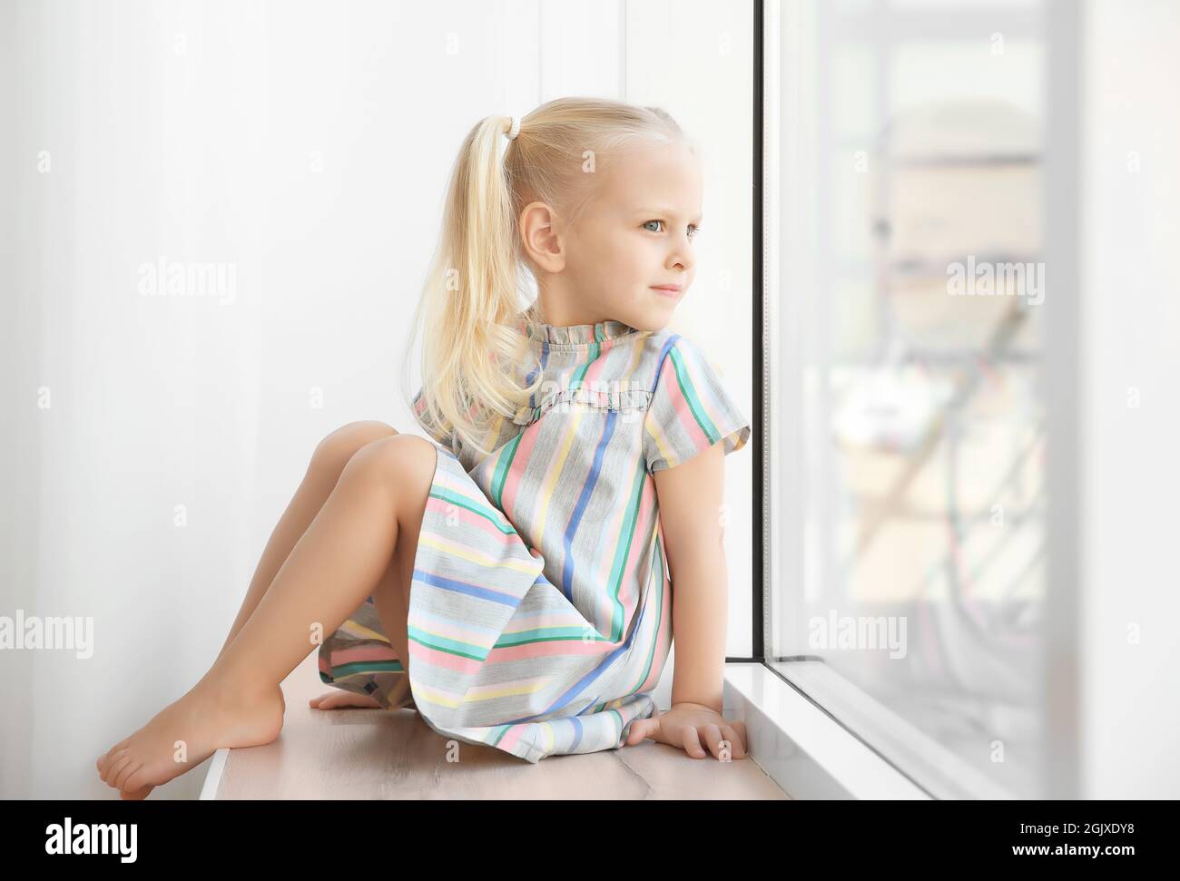 Cute little girl sitting on windowsill Stock Photo - Alamy
