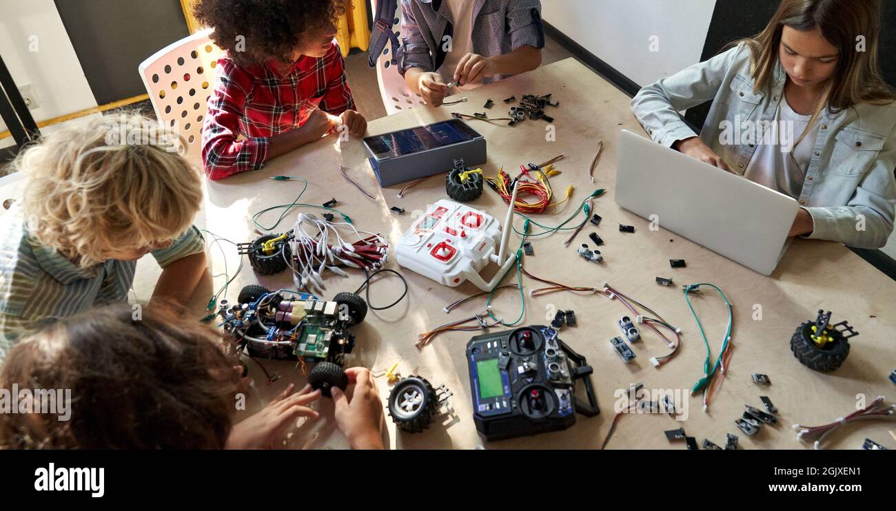 Group of multiracial schoolkids at stem class building robot. Table top view. Stock Photo