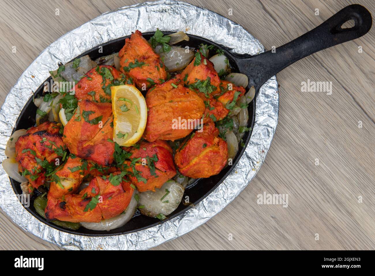 Overhead view of seasoned chicken served on skillet from Indian restaurant cooked and seasoned perfectly. Stock Photo