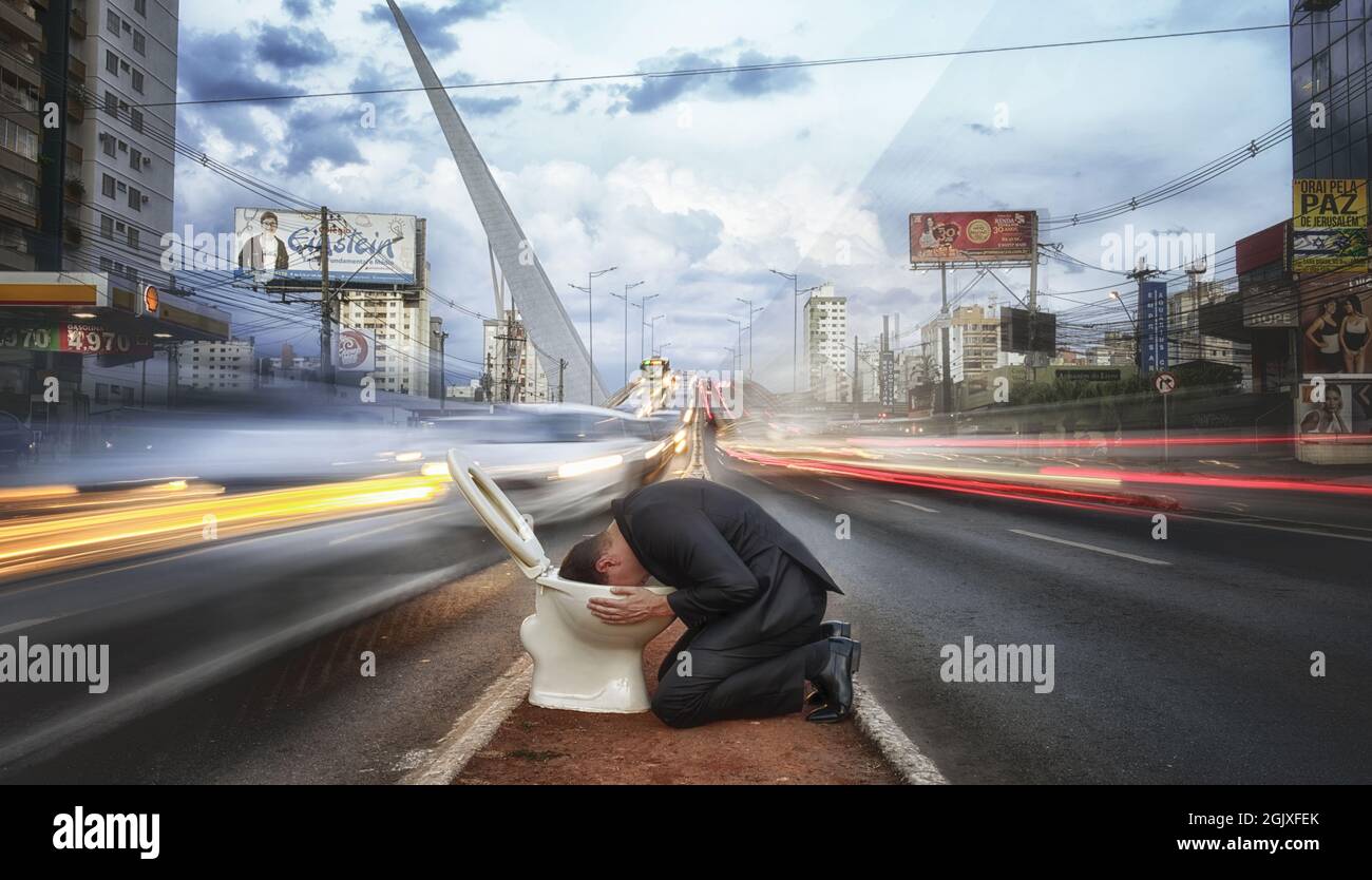 Man hides his head in a toilet during rush hour - Burnout in urban life Stock Photo